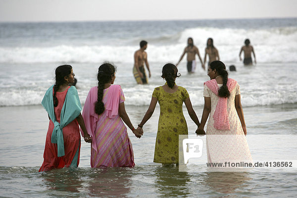 IND  India  Kerala  Trivandrum : Lighthouse Beach  Kovalam Beaches. Young ladies  in their saris  walking through the water on the beach. |