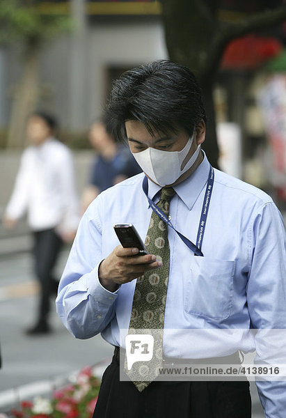 JPN  Japan  Tokio: Japaner telefonieren mit dem Handy  Mundschutz