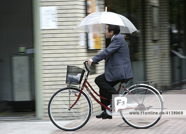Cyclist with umbrella Tokyo Japan