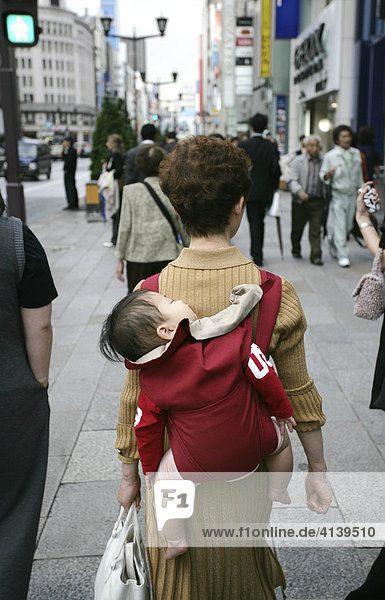 Frau traegt ein schlafendes Baby in einem Tragegurt auf dem Rücken  Ginza  Tokio  Japan  Asien
