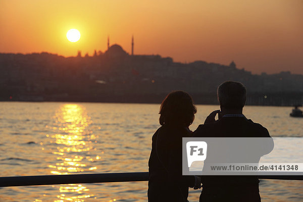 Stadtpanorama  Touristen  bei Sonnenuntergang am Goldenen Horn  von der Galatabrücke aus gesehen  Istanbul  Türkei