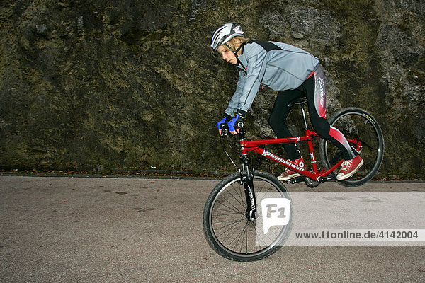 Young mountain biker  standing on his front wheel