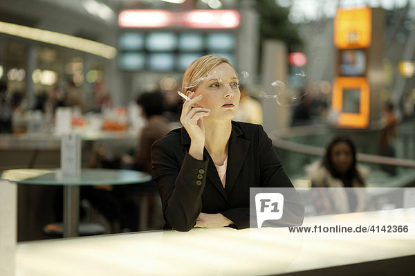 Young woman smoking at an airport cafÈ