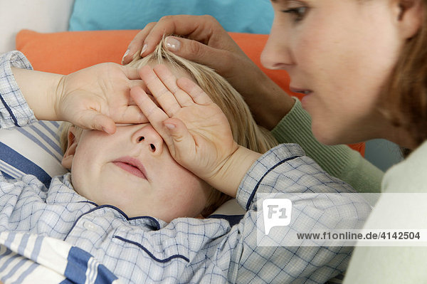 Mutter bringt ihren Sohn ins Bett  Kind reibt sich die Augen