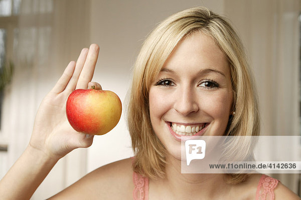 Junge  blonde Frau mit Apfel  lächelt
