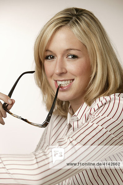 Junge  blonde Frau in gestreifter Bluse  lächelt  mit Brille