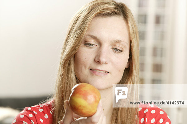 Blonde woman looking at apple