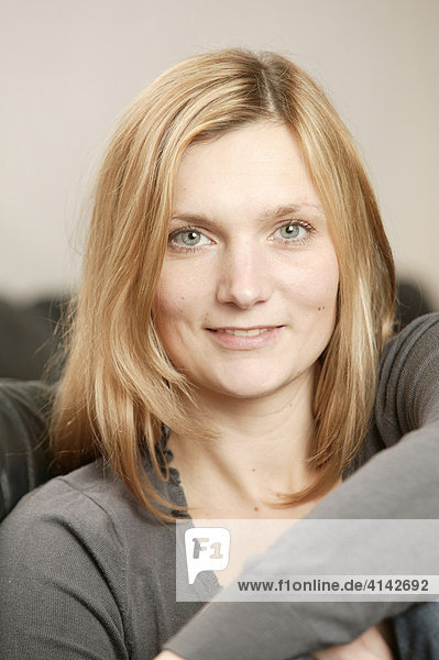 Smiling blonde woman on brown couch