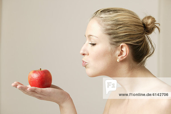 Junge  blonde Frau mit Apfel  küssend