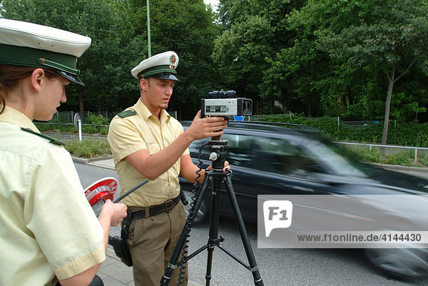 DEU  Germany  Essen: Traffic speed control in a speeding zone of 30 km/h near a school  with a laser measure gun. Daily police life. Officer from a city police station.