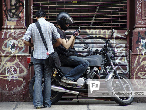 USA  Vereinigte Staaten von Amerika  New York City: Soho. Motorradfahrer  sms tippen.