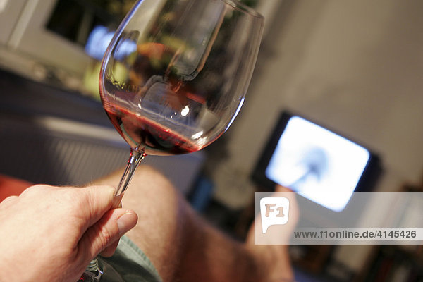 DEU  Germany : man in front of an TV. Glas of red wine.