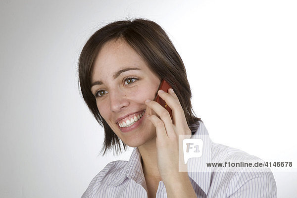Junge Frau telefoniert lächelnd mit dem Handy