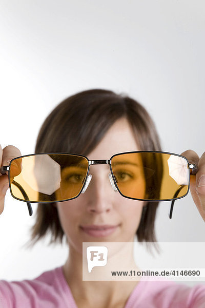 Junge Frau schaut durch Sonnenbrille