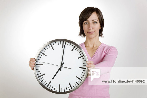 Junge Frau hält eine große Uhr