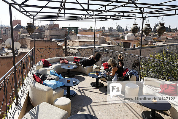 Junge Touristinnen relaxen auf der Dachterrasse des Café Arabe  Blick über die historische Medina  Marrakesch  Marokko  Afrika