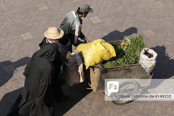 Men pushing cart loaded with raw green vegetables and sacks  Djemaa el Fna  Marrakech  Morocco  Africa