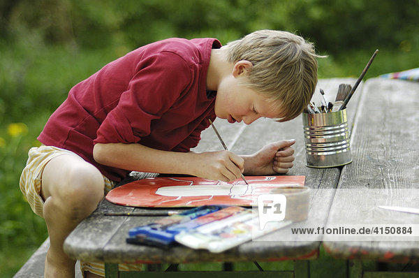 Junge  10 Jahre  malt im Garten