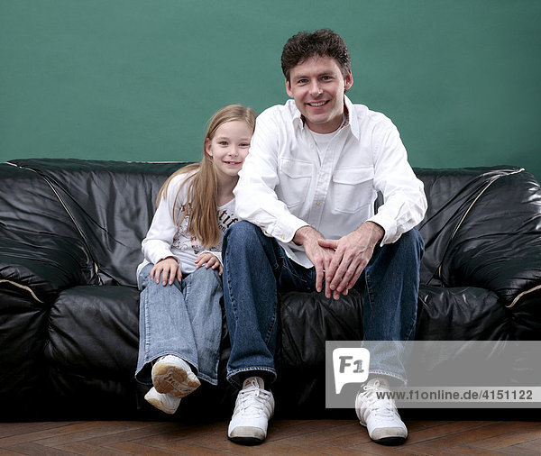 Vater und Tochter sitzen entspannt auf dem Sofa