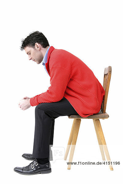 Man wearing red jacket sitting on an old wooden chair