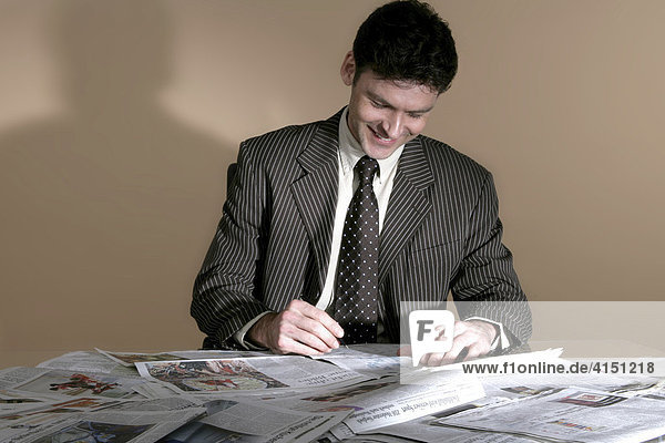 Geschäftsmann sitzt vor vielen Zeitungen
