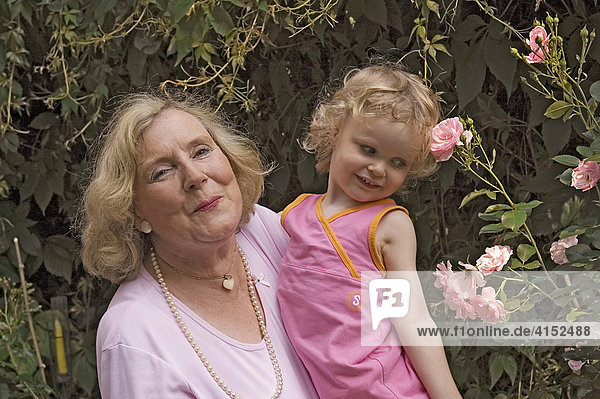 Proud grandmother holds her granddaughter on her arms