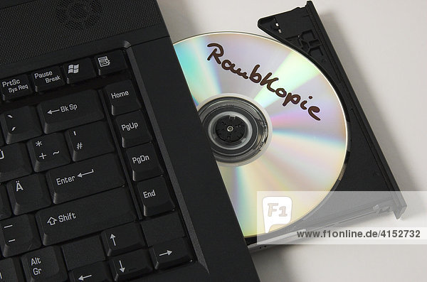 Eine CD mit der Aufschrift Raubkopie liegt im CD Laufwerk eines Notebook Computers