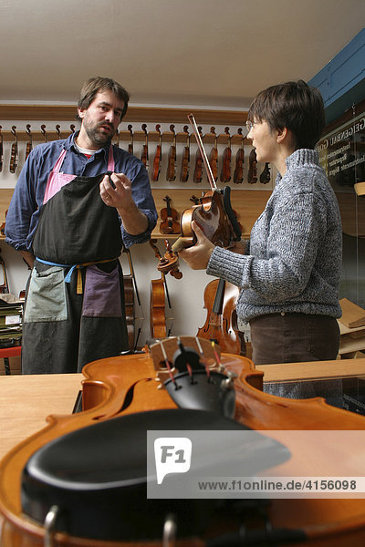Geigenbauer mit Kundin im Verkaufsraum