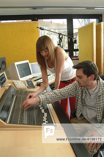 Junge Frau mit Techniker am Mischpult eines Tonstudios