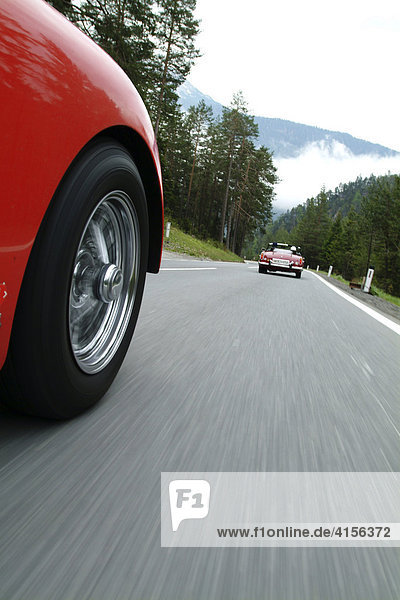 Roter TR 3 von aussen waehrend er Fahrt hinter roten Oldtimer