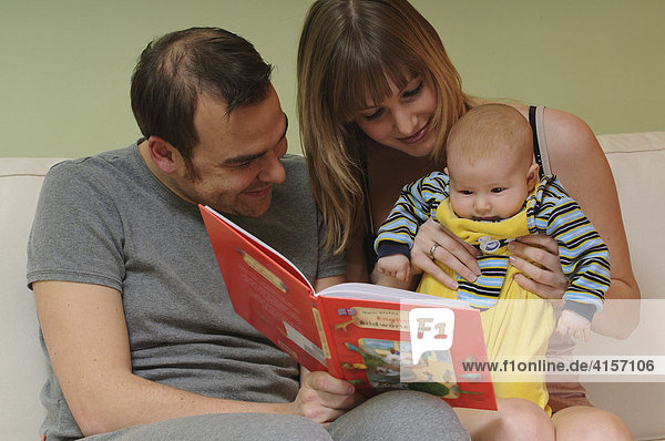 Vater Frau und Baby sehen sich Bildwörterbuch an