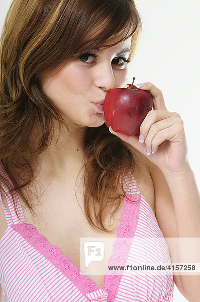 Hübsche junge braunhaarige Frau isst einen roten Apfel