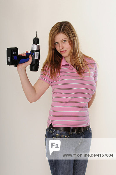 Young long-haired woman wearing pink polo shirt holding a power drill