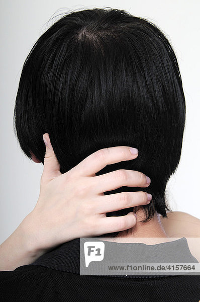 Hände einer Frau umfassen Kopf eines jungen Mannes  schwarze Haare  von hinten