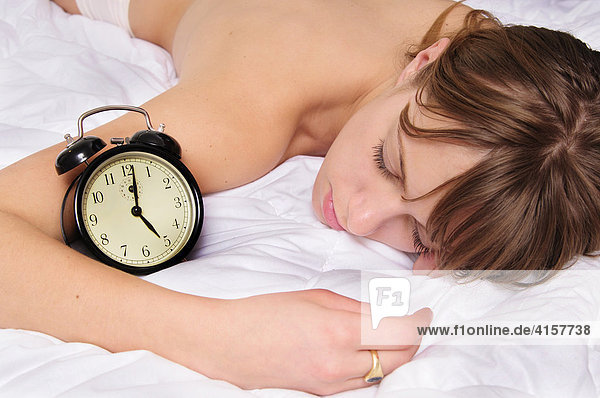 Blonde woman asleep with alarm clock set for 5 o'clock  five am