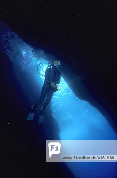 Diver is swimming in a big cave  Mediterranean Sea.