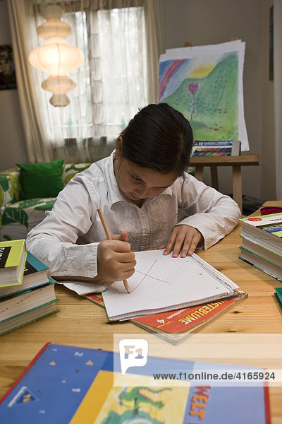 Young schoolgirl doing homework in nursery  drawing angrily in her notebook