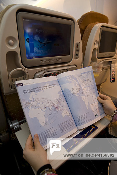 Frau studiert die Flugstreckenkarte in einem Flugzeug