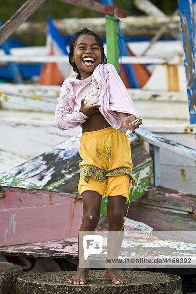Young laughing girl standing in front of fishing boats  Lombok Island  Lesser Sunda Islands  Indonesia
