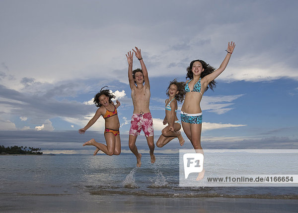 Four children jumping with joy on the beach  Lombok Island  Lesser Sunda Islands  Indonesia  Asia