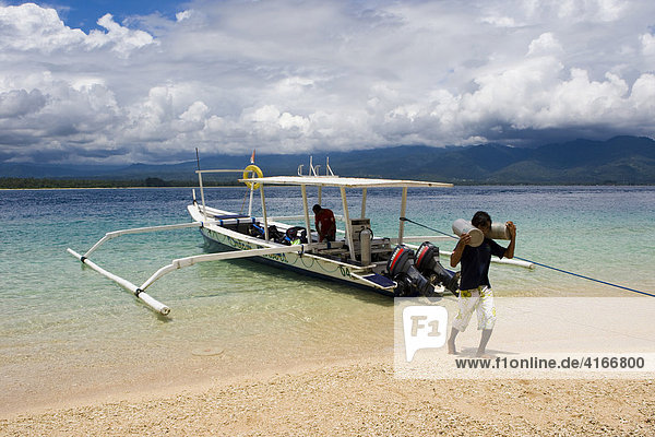 Mann trägt Tauchflaschen von einem Tauchboot  Insel Trawangan  Kleine Sunda-Inseln  Indonesien  Asien