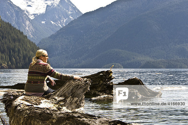 Woman sitting on the bank of Pitt Lake  British Columbia  Canada  North America