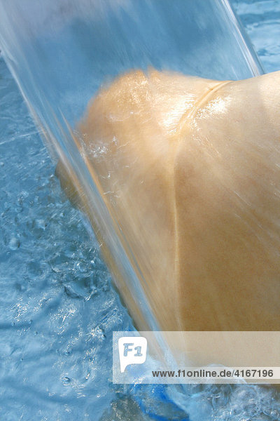 Eine Frau lässt ihren Rücken und ihre Schultern von einem warmen Wasserstrahl massieren  Badewanne  Whirlpool  Thermalbad.