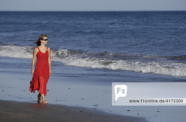 Mädchen in rotem Kleid am Meer