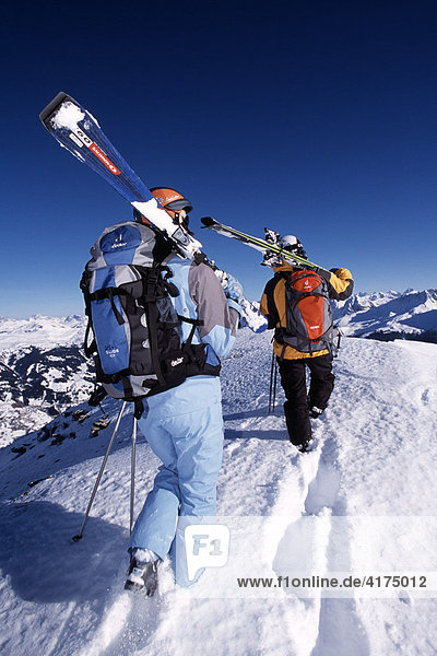 Skifahrer tragen ihre Skier hoch