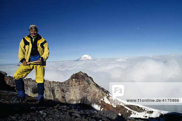 Mountain climber at the summit of Mt. Tungurahua  Mt. Chimborazo in the background  Banos  Ecuador  South America