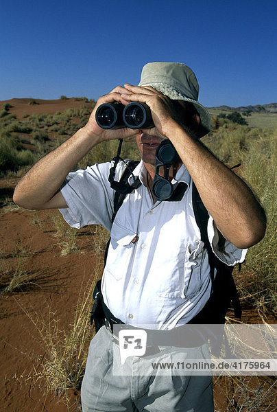 Man looking through binoculars  NamibRand Nature Reserve  Namibia  Africa