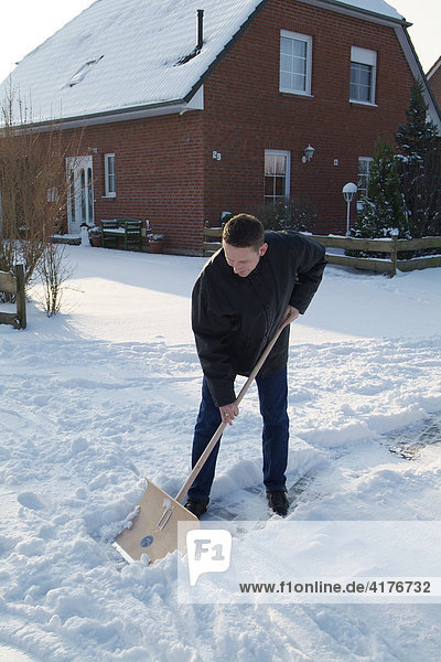 Mann schiebt schnee vom fussweg