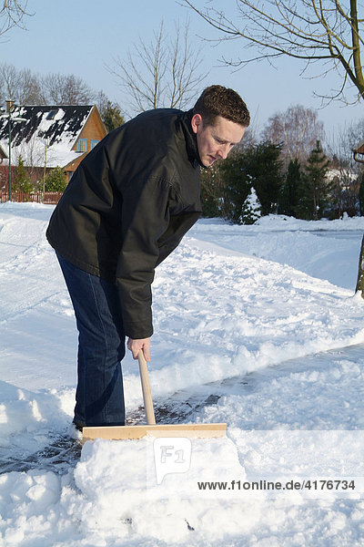 Mann schiebt schnee vom fussweg