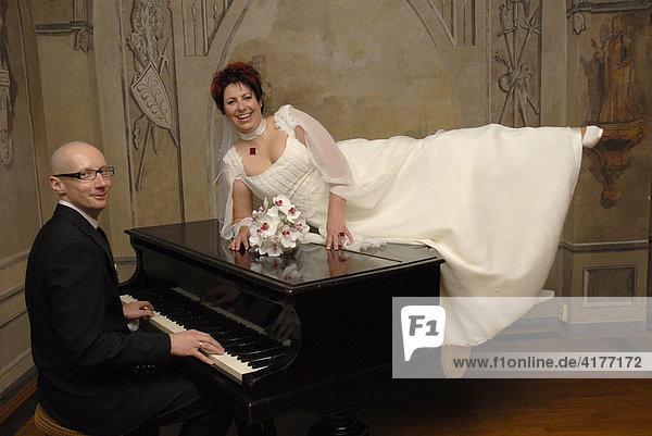 Bridal couple sitting by a piano